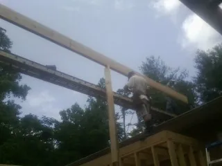 Carpenter setting a ridge beam over a new addition frame — Ice Dam Removal by Roofing Brothers in Burkeville