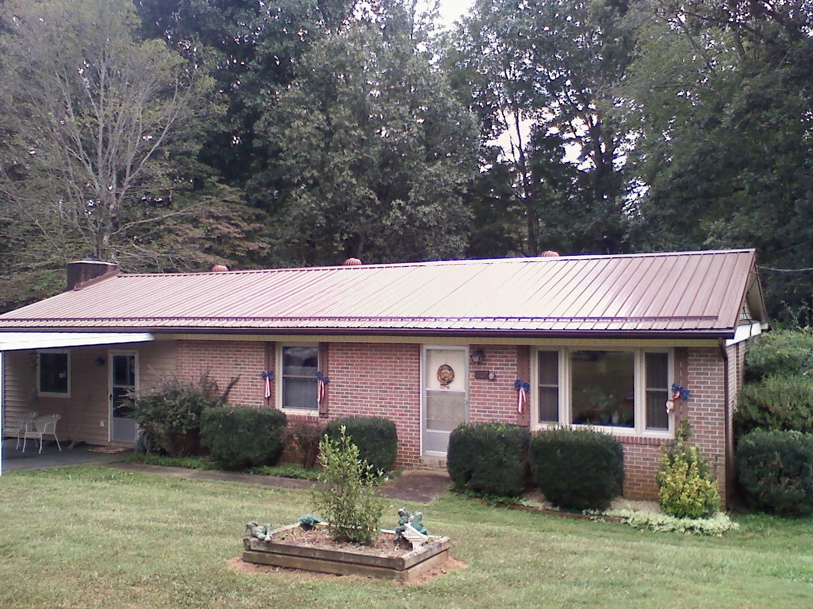 Bronze metal roof on a brick ranch home with a carport in Burkeville