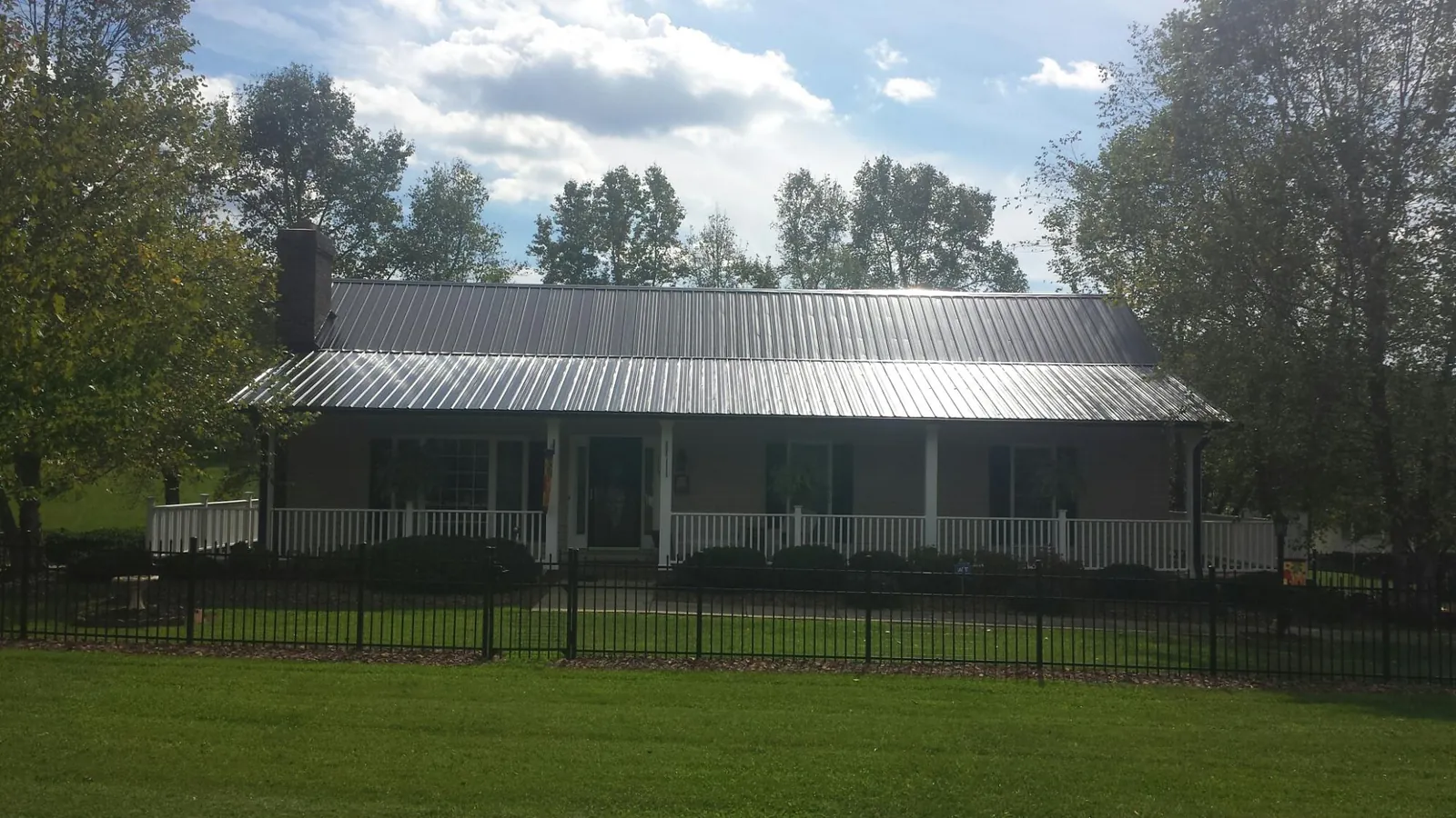 Gray metal roof on a brick ranch with a full width front porch — Gutter Guard Installation work by our crew in Burkeville