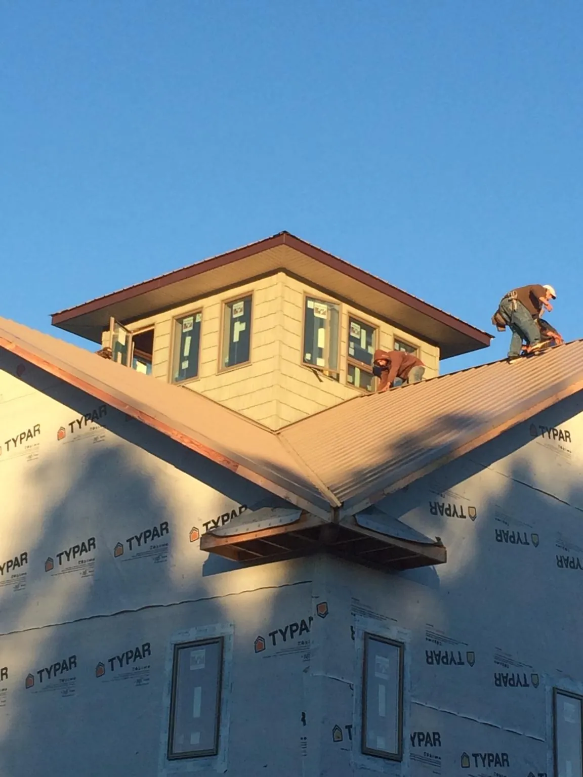 Roofers working around a rooftop cupola on a new metal roof at sunset — Roof Waterproofing in Burkeville by Roofing Brothers